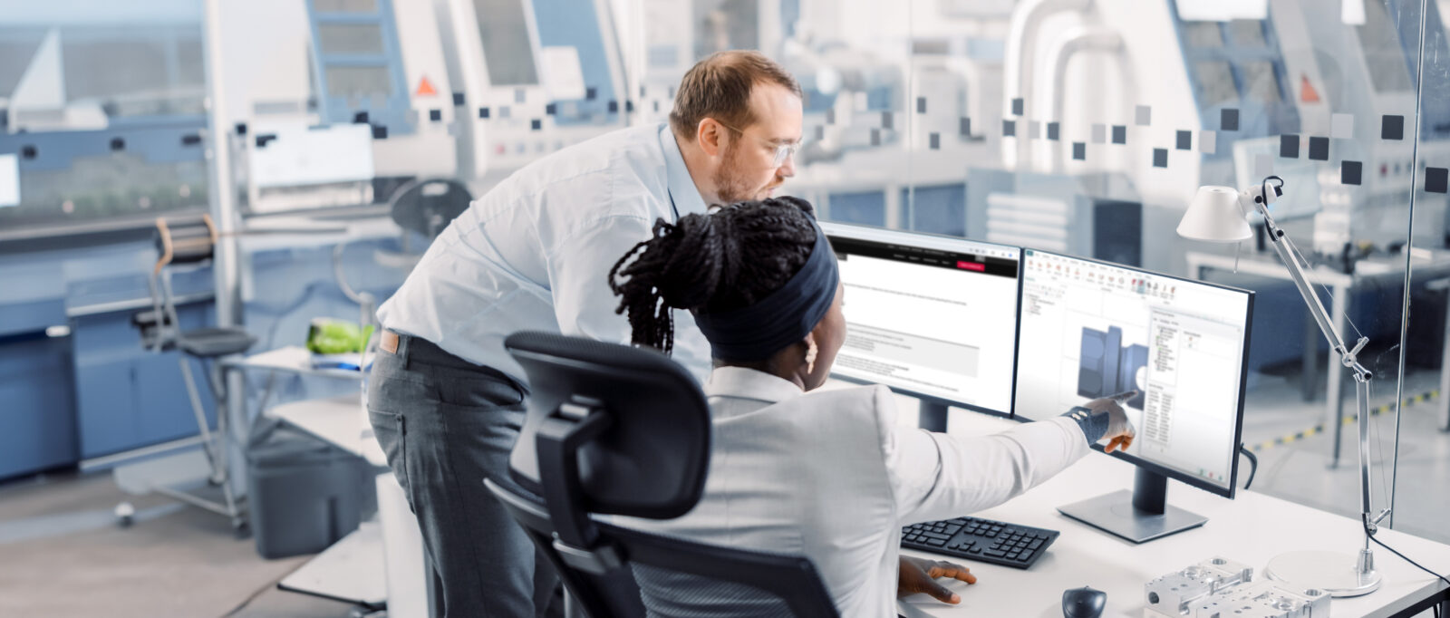 A man and a woman collaborating in front of a computer workstation