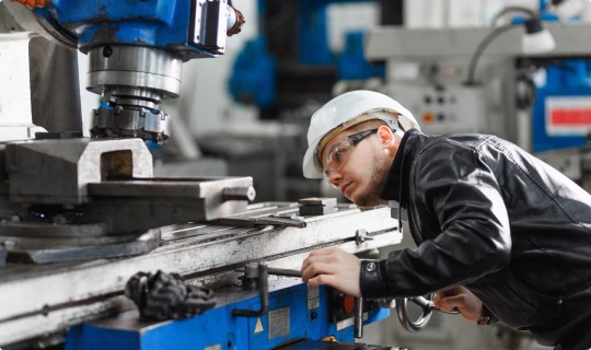 Man wearing white hard hat working machine