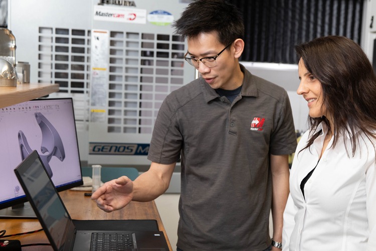 A Mastercam trainer working with a woman in front of a laptop